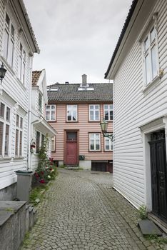 typical street in Bergen in Norway with white wooden houses and flowers at the street