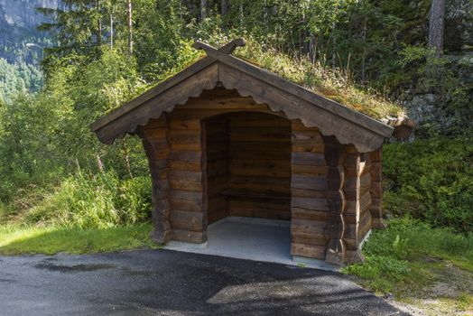 Bus stop on the side of the road on the country side in norway. The Majestic mountains landscape, fjord in Norway with wooden bus stop. traditional wooden bus stop with grass covered roof,