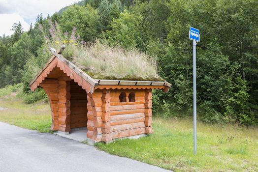 Bus stop on the side of the road on the country side in norway. The Majestic mountains landscape, fjord in Norway with wooden bus stop. traditional wooden bus stop with grass covered roof,