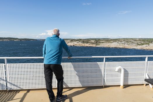 adult man in blue sweater on ferry from Norway to Sweden with the caost of sweden as background