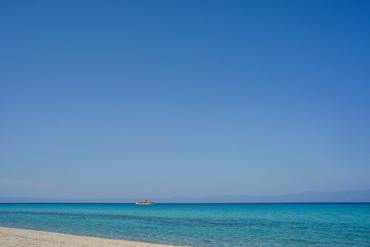 An empty beautiful seashore with clear sky and a tourist boat.