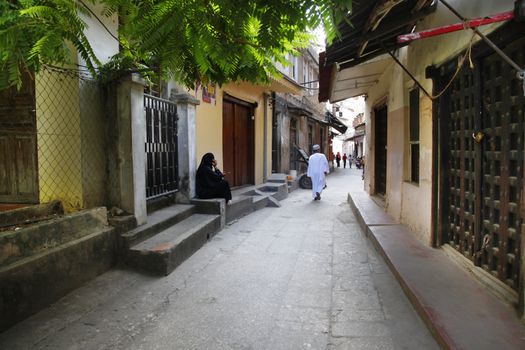 Stone town, Tanzania - January 01, 2016: Stone Town. Woman in Zanzibar all have to wear black burka when they go outside, even girls have to wear scalf on their heads. It is a Muslim life stile. Streets of the town are always lively. 