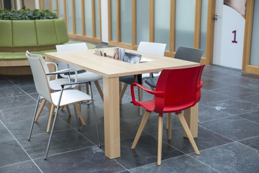 empty waiting room with red white and gray chairs and wooden tablew with papers and tabloids
