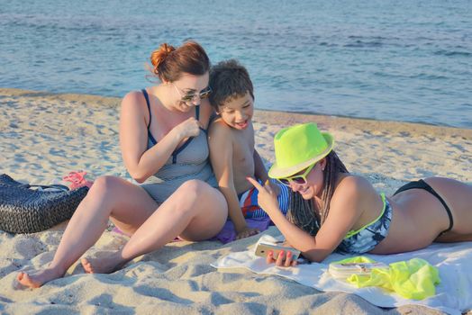 A group of three - two females and a kid are making selfie on a quiet beach.