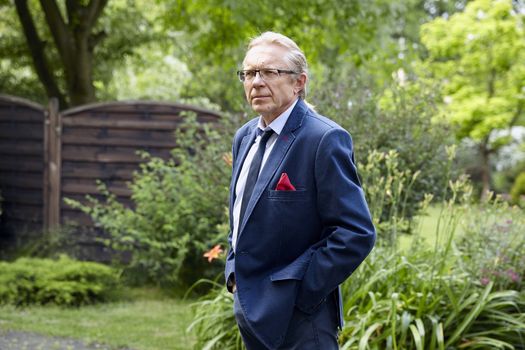 Portrait of a pensive middle-aged man in the garden. Natural sunlight.