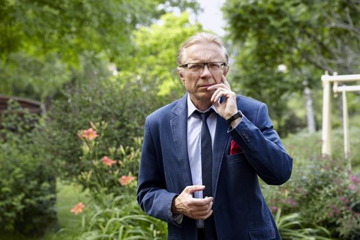 Portrait of a worried middle-aged man in the garden. Natural sunlight.