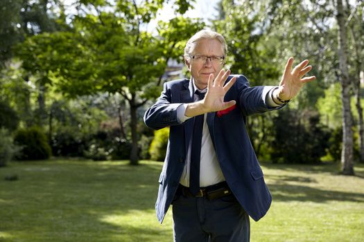 Portrait of gesticulate man in the garden at sunny day. Natural sunlight.