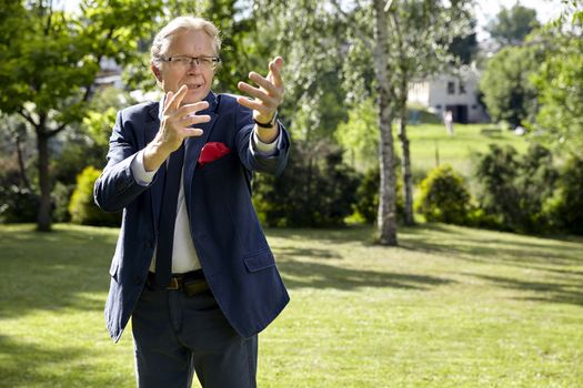 Portrait of gesticulate man in the garden at sunny day. Natural sunlight.