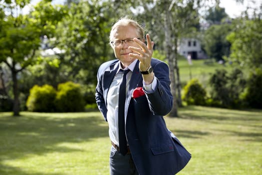 Portrait of gesticulate man in the garden at sunny day. Natural sunlight.