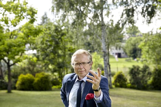 Portrait of gesticulate man in the garden at sunny day. Natural sunlight.