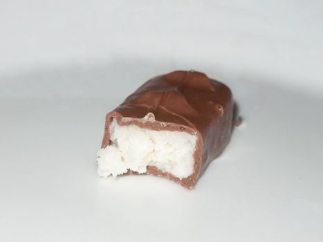 brown chocolate bounty bar on white surface sweets food half eaten; essex; england; uk