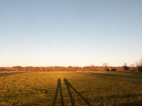 two human silhouettes large legs field of grass background; essex; england; uk