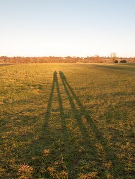 two human silhouettes large legs field of grass background; essex; england; uk