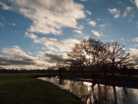 sunset cloudy blue sky trees silhouette lake river dedham; essex; england; uk