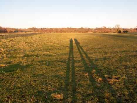 two human silhouettes large legs field of grass background; essex; england; uk