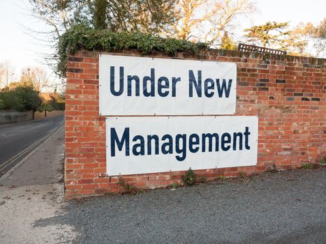 big large white and black sign on brick wall under new management; essex; england; uk