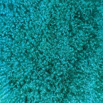 Turquoise colored sheepskin background. Soft and fluffy natural luxurious material.