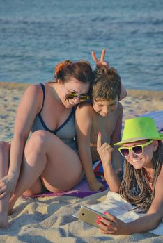 A group of three - two females and a kid are making funny rabbit ears selfie on a quiet beach.