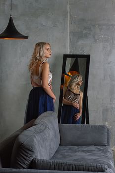 Young beautiful woman in cocktail dress standing near mirror