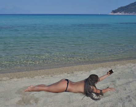 Sexy women taking selfie on a beautiful quiet sea beach with smartphone.