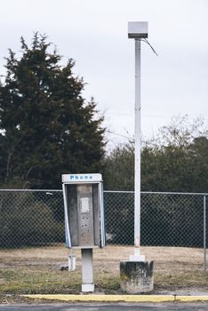 Abandoned payphone box next to a lamp post. Phone is missing.