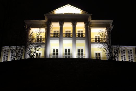 an ancient building with columns. night and a bright light from the windows.