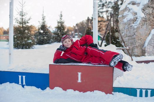 A little boy in red clothes is skiing in a pine forest