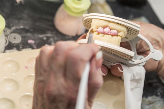 Female Dental Technician Applying Porcelain To A 3D Printed Implant Mold In The Lab.