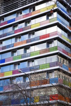 Bottom view of a modern building with colored and numbered glass balconies.
