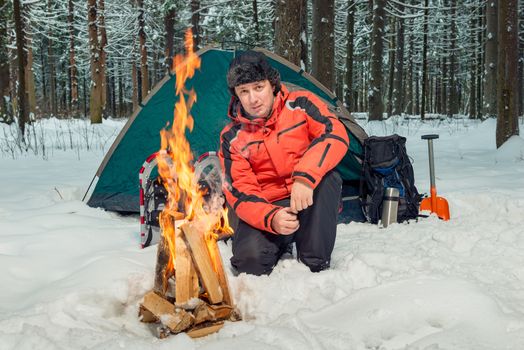 a tourist in a winter forest in extreme conditions is building a fire