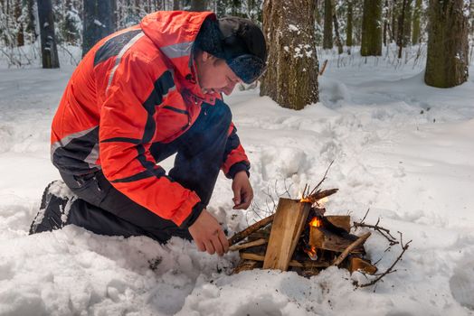 a lost frozen tourist tries to build a fire in a winter cold forest