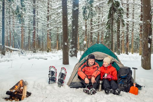 a couple on an expedition in the winter mountains and the forest, a break for tea