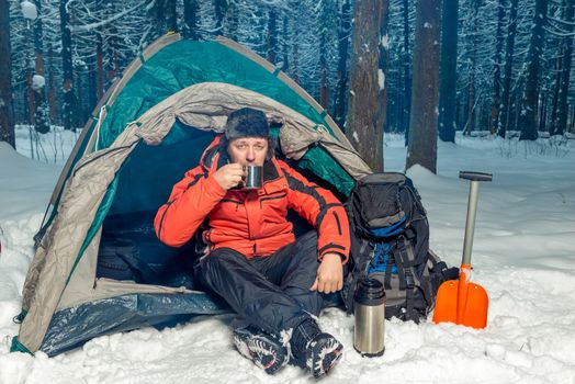 a lost tourist in the winter forest drinking tea while sitting in a tent