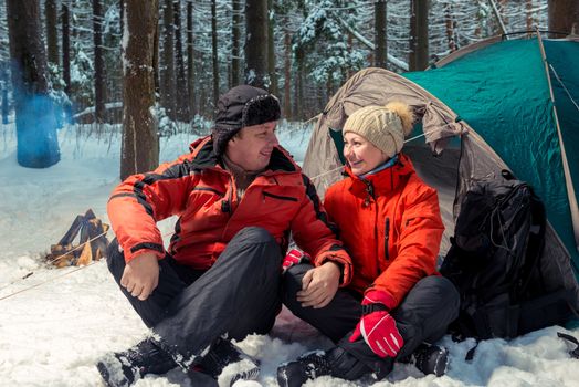 happy couple of active tourists outdoors in the winter forest on a hike