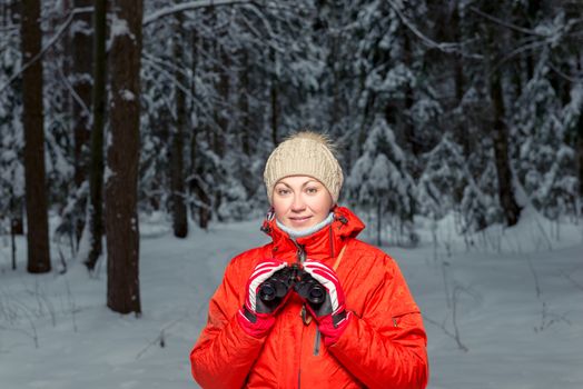 beautiful woman tourist with binoculars in a winter forest