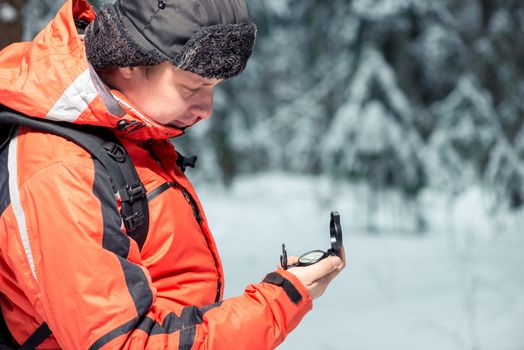 a lost tourist looking at a compass, shooting in a winter forest