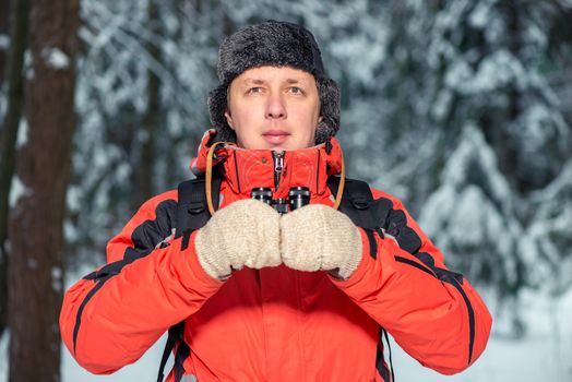 portrait of a man in a winter forest with binoculars