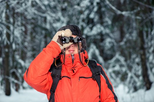 a lost tourist man in a winter forest with binoculars