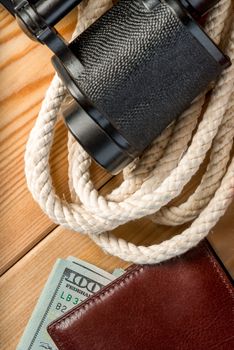 wallet, strong rope and binoculars close-up on a wooden floor