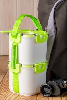 food containers and backpack ready for a picnic on a wooden table