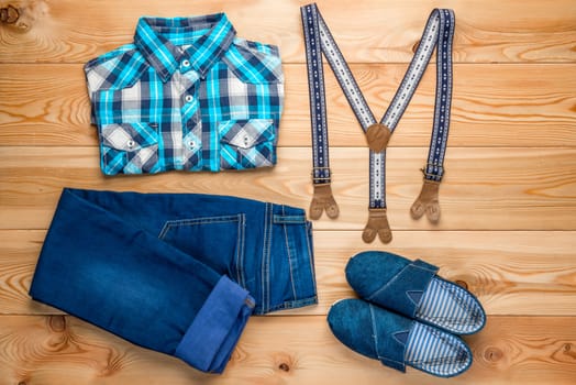 set of clothes for a boy in a rural style top view on a wooden floor