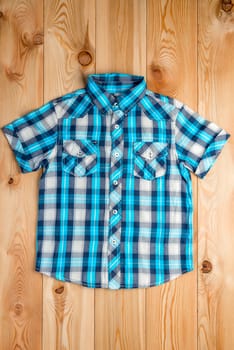 blue checkered shirt for a boy in a rural style on the wooden floor
