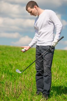 Golfer in full length on the field with balls and a golf club