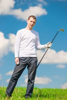 man with balls and putter for golf on green field posing