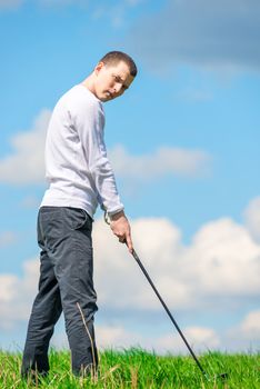 A young successful golfer prepares to hit the ball with a golf club on the field