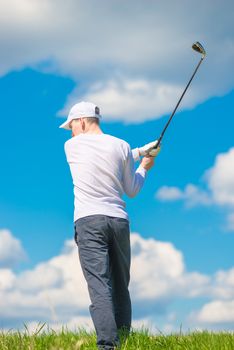 man swinging his club before hitting the ball against the blue sky