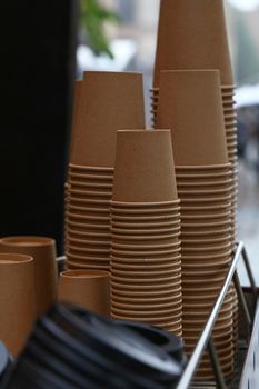 Close up stack of brown disposable kraft paper cups on coffee machine, low angle view