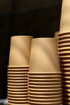 Close up stack of brown disposable kraft paper cups on coffee machine, low angle view