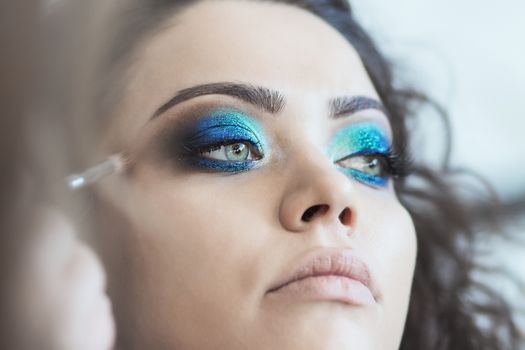 Professional make-up artist prepares a model for a photo shoot