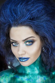 Portrait of a beautiful mermaid girl. Wet skin, wet hair, glitter and scales on his face. Blue eyes. The image on Halloween. Advertising Space.